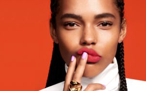 A model for beauty brand Mecca looks into the camera wearing red lipstick